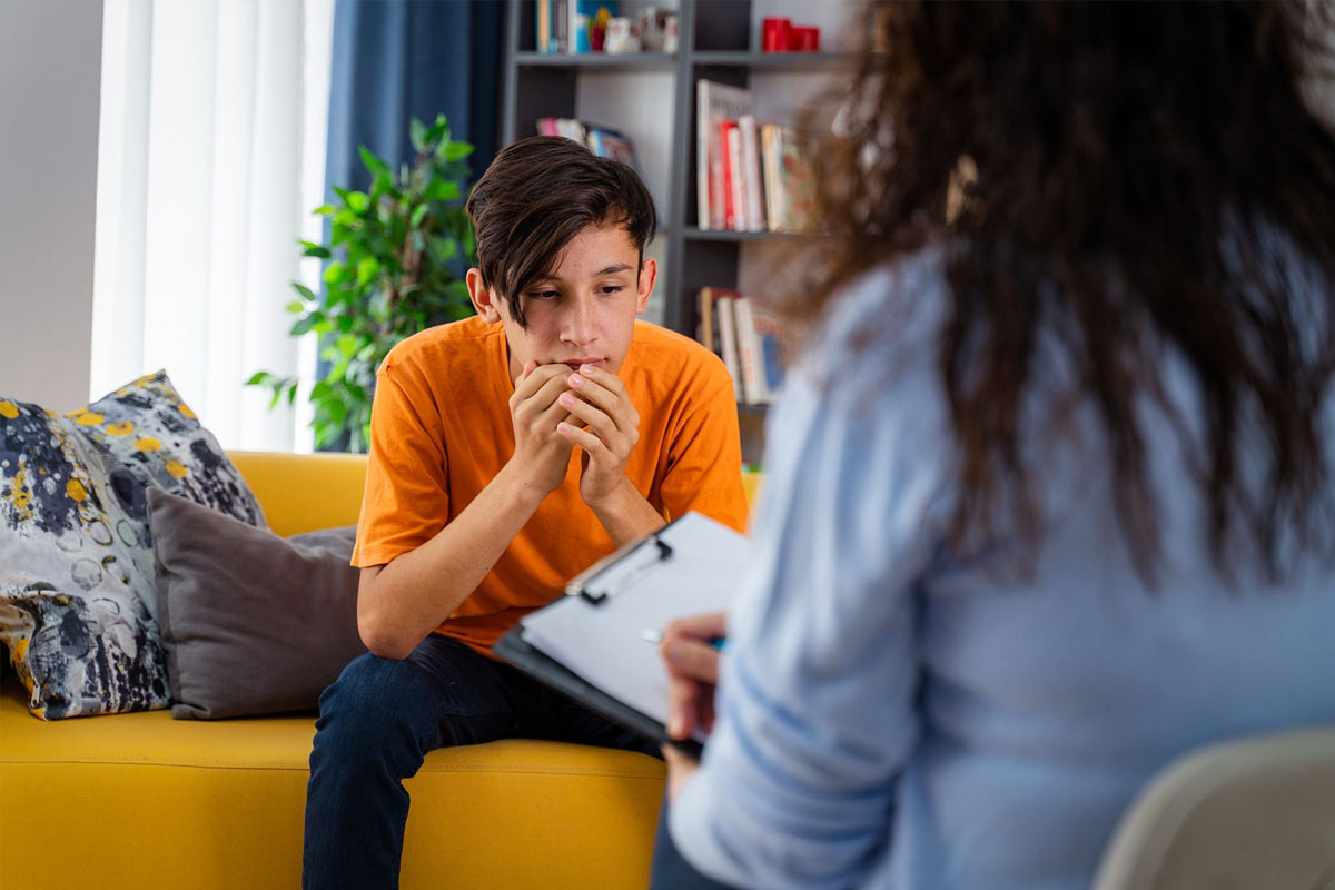 Female psychologist counseling teenage boy in office