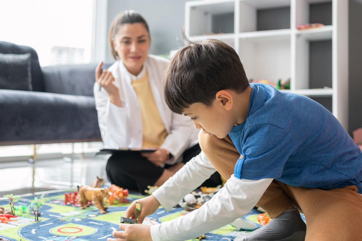 boy playing with plastic toys on play mat