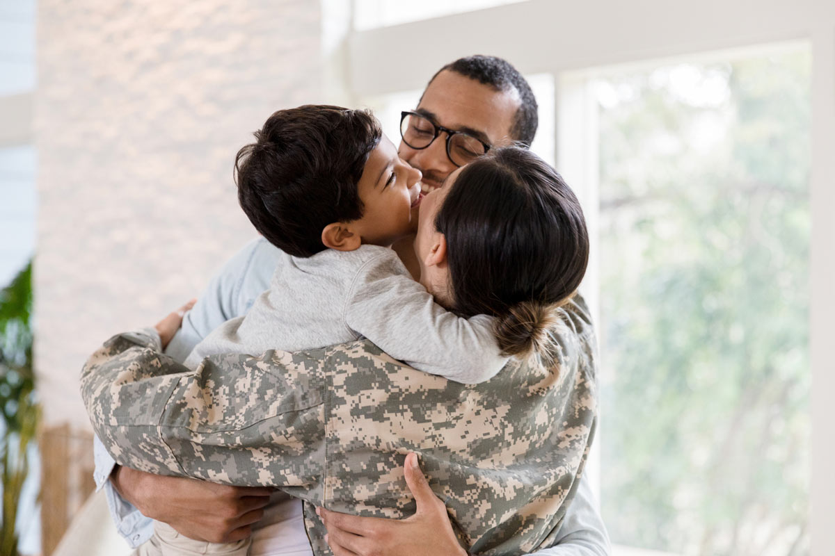 military mom hugging family