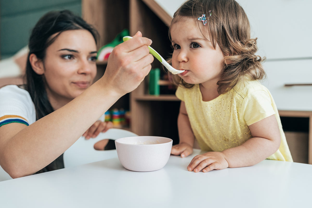 Mom feeding daughter cereal