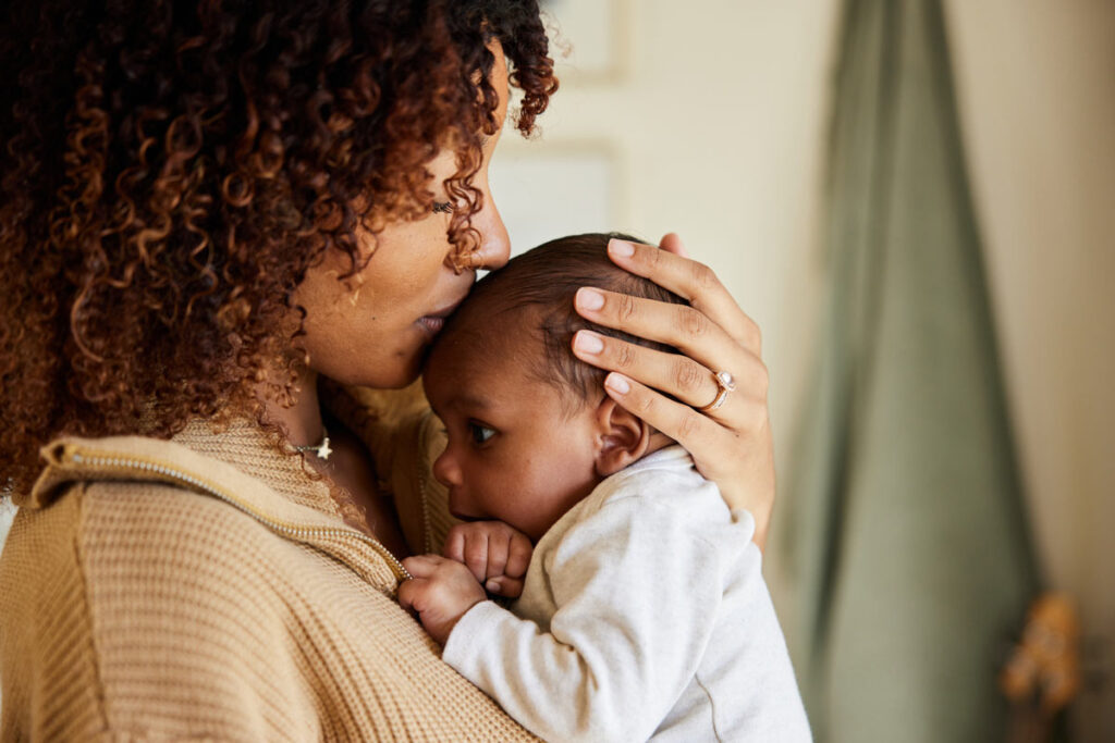 mom kissing newborn on head