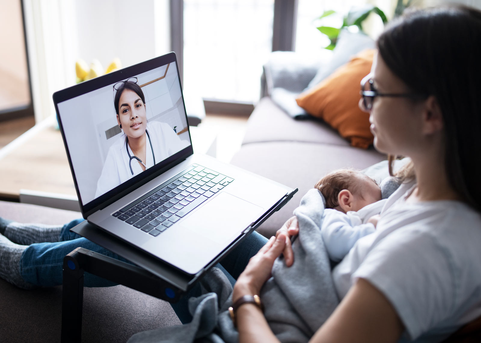 Mother holding baby during Telehealth session from home