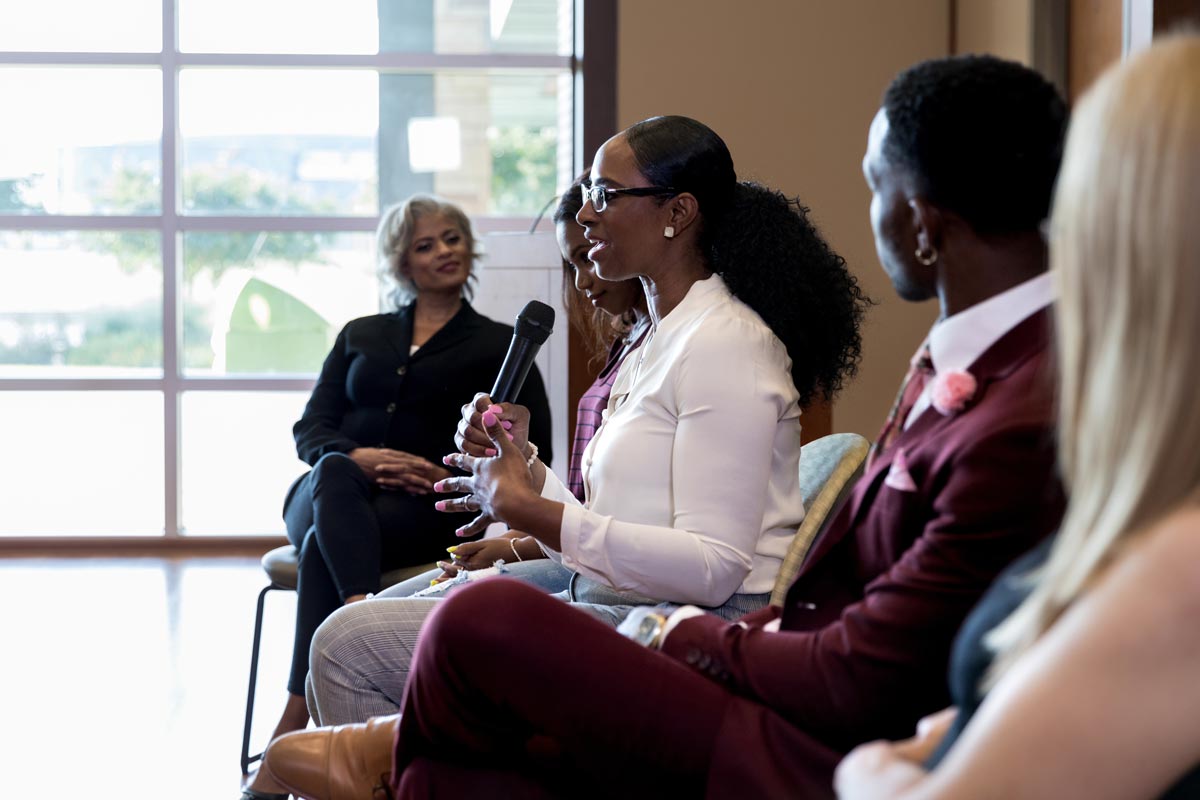 female panel member gestures and uses the microphone