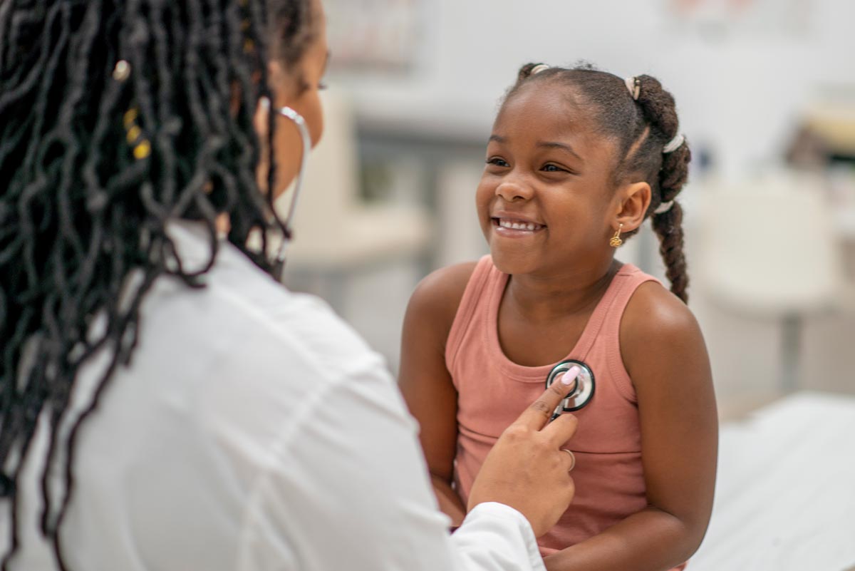 Doctor listening to little girl's heart