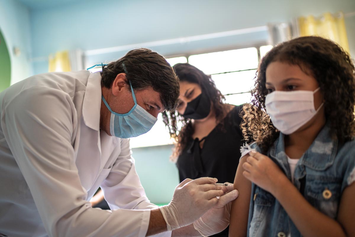 girl getting vaccinated with her mother in vaccination center