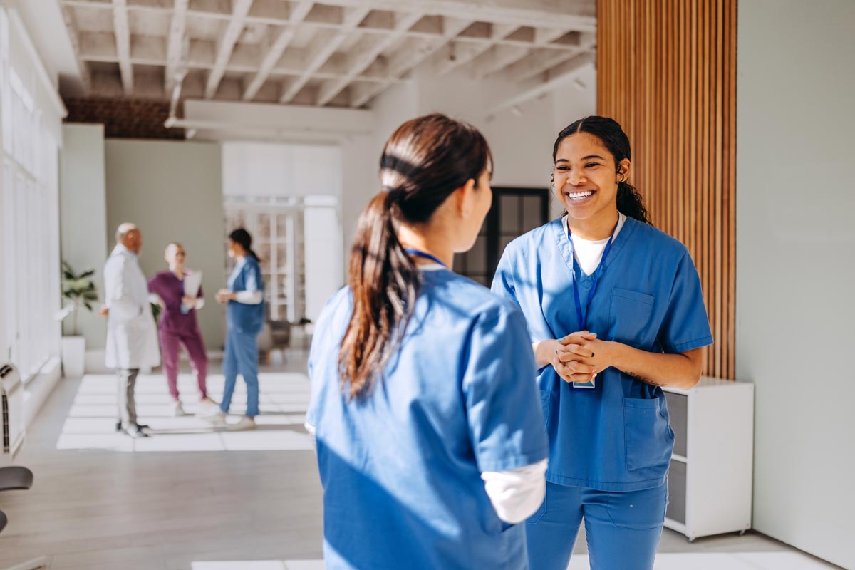 Two female doctors discussing work together at hospital corridor