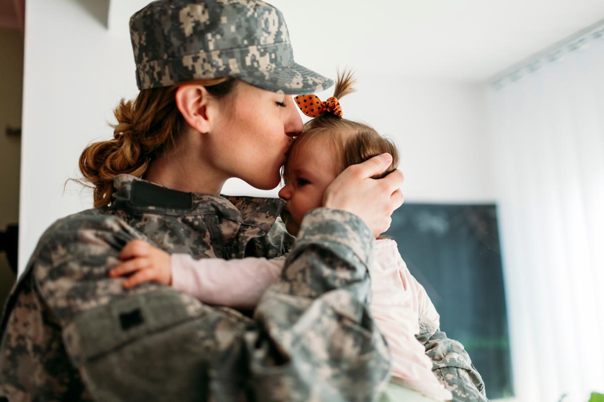 Military mom kissing her little girl